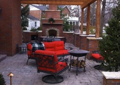 pergola-covering-brick-patio-with-fireplace-in-background